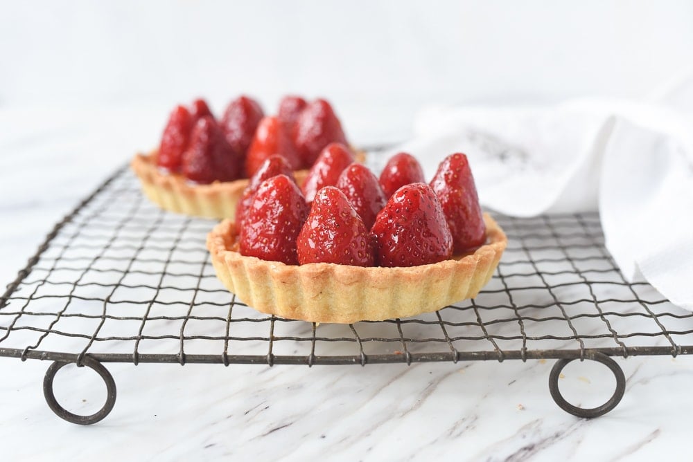 two strawberry tarts on a cooling rack