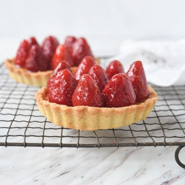 two strawberry tarts on a cooling rack