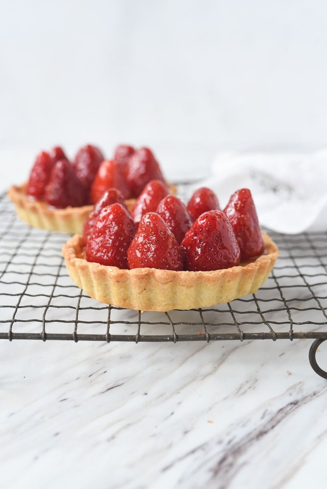 two strawberry tarts on a cooling rack