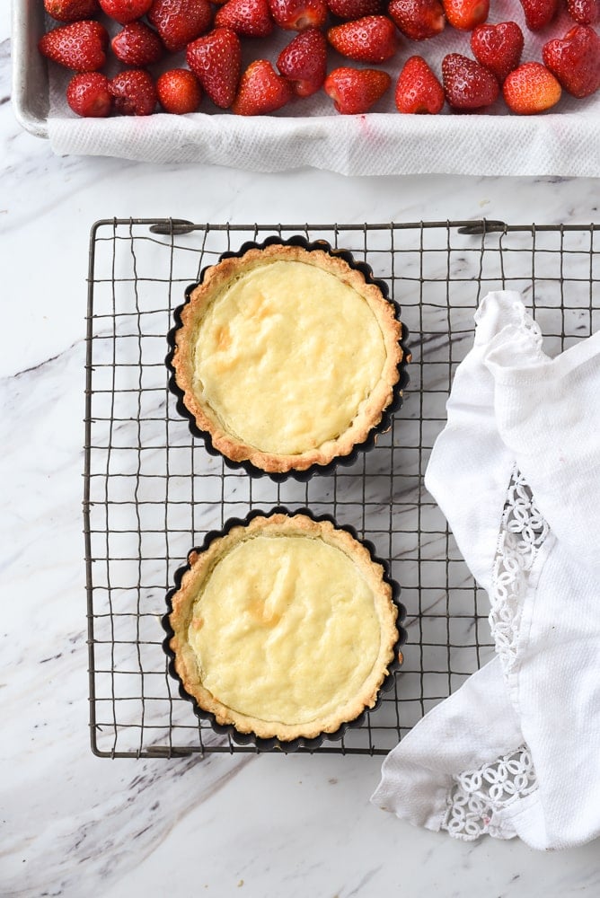 two tarts with custard cooling on a rack
