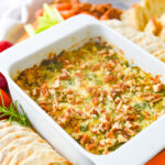 bowl of artichoke dip with pecans on top