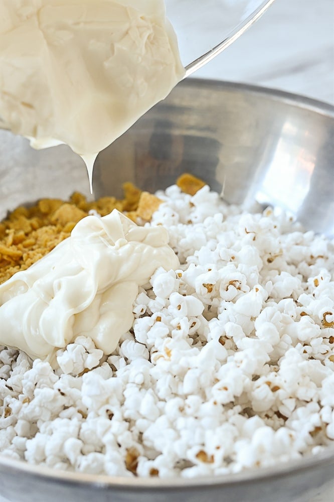 pouring white chocolate over popcorn