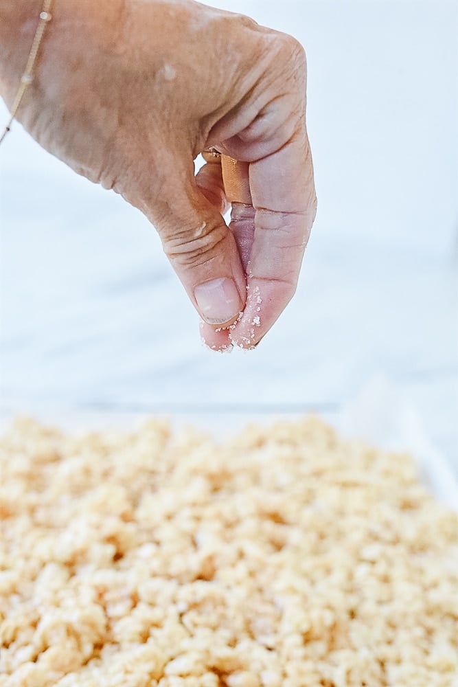 Sprinkling salt onto rice krispie treats.