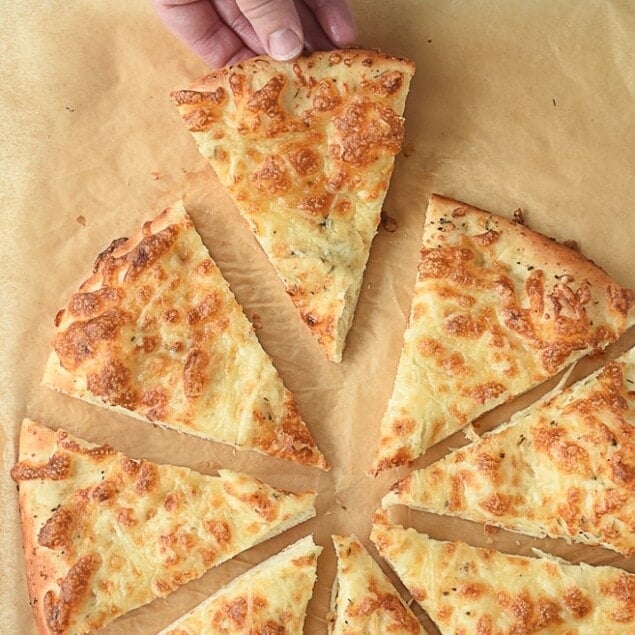 hand holding a piece of cheesy bread