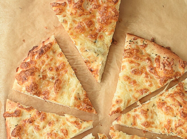 hand holding a piece of cheesy bread