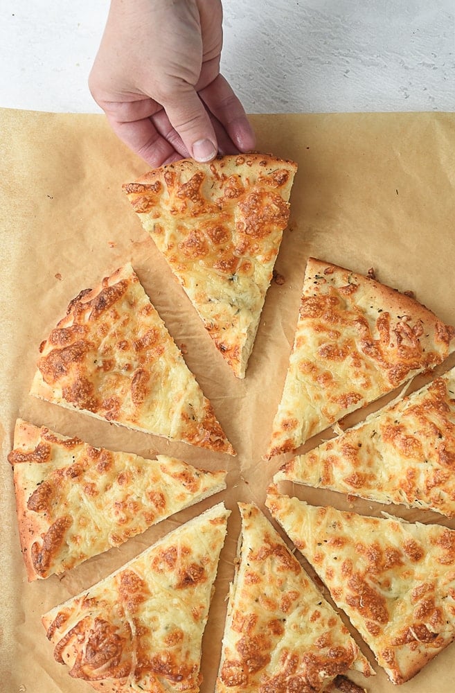 hand holding a piece of cheesy bread