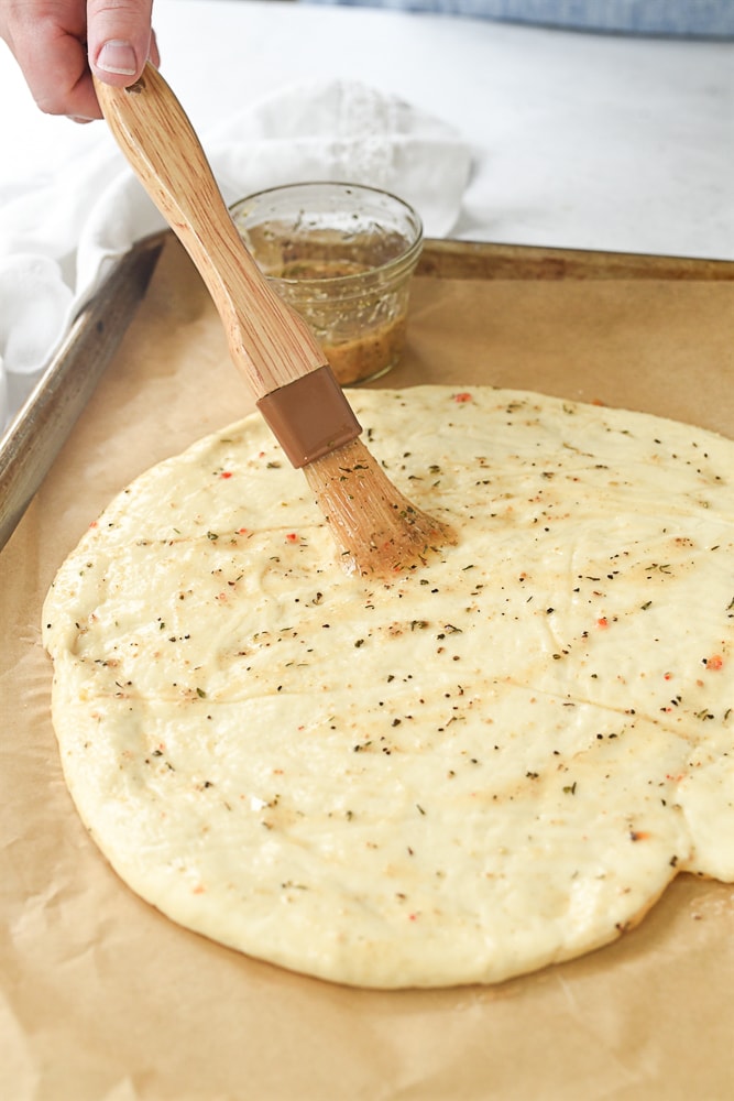 Brushing herbs on pizza dough