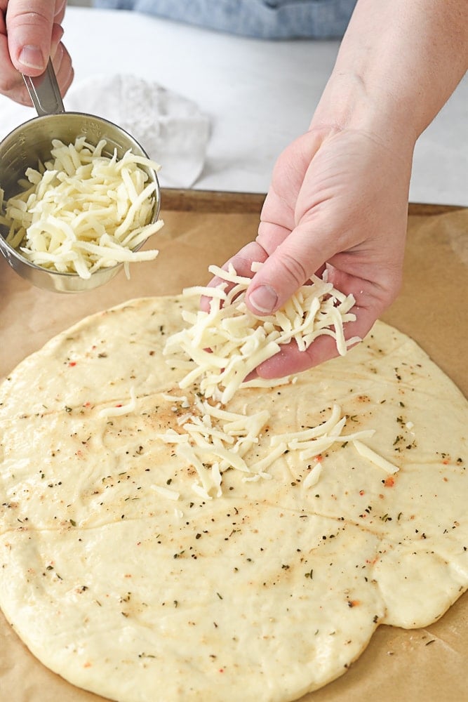 sprinkling cheese on pizza dough
