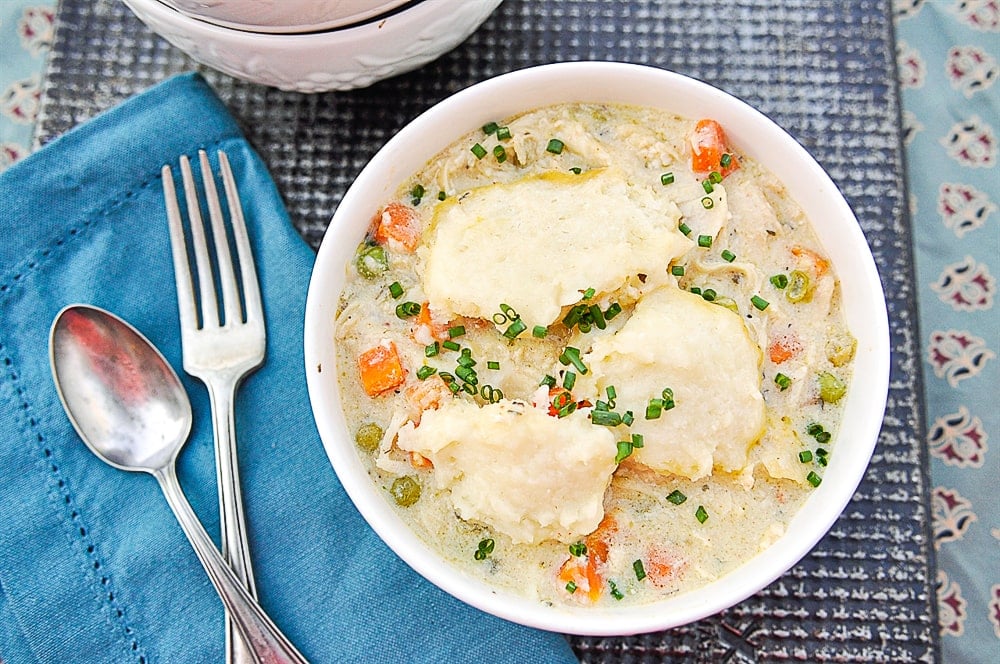 fork and spoon with bowl of chicken and dumplings
