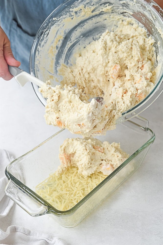 scooping cheese bread batter into pan
