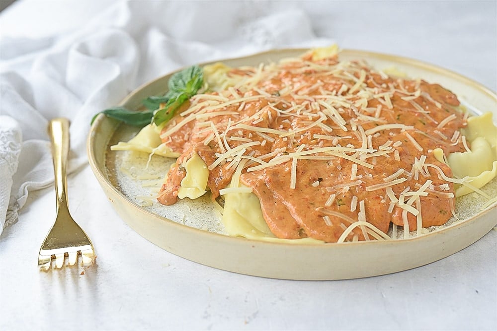 plated of red pepper cream sauce over ravioli