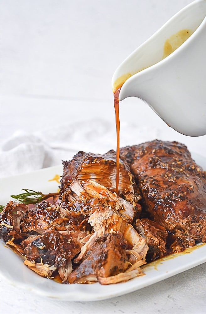 pouring sauce over pork roast