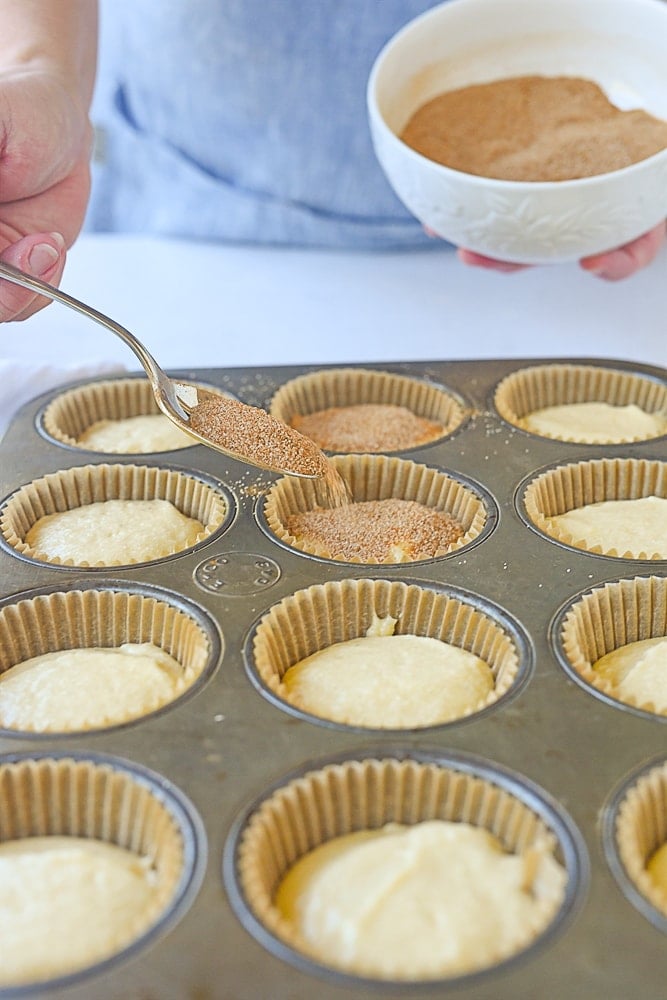 sprinkling cinnamon sugar on top of muffins