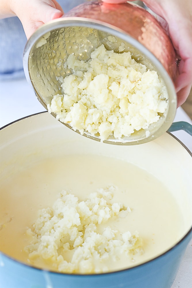 adding potatoes into potato soup