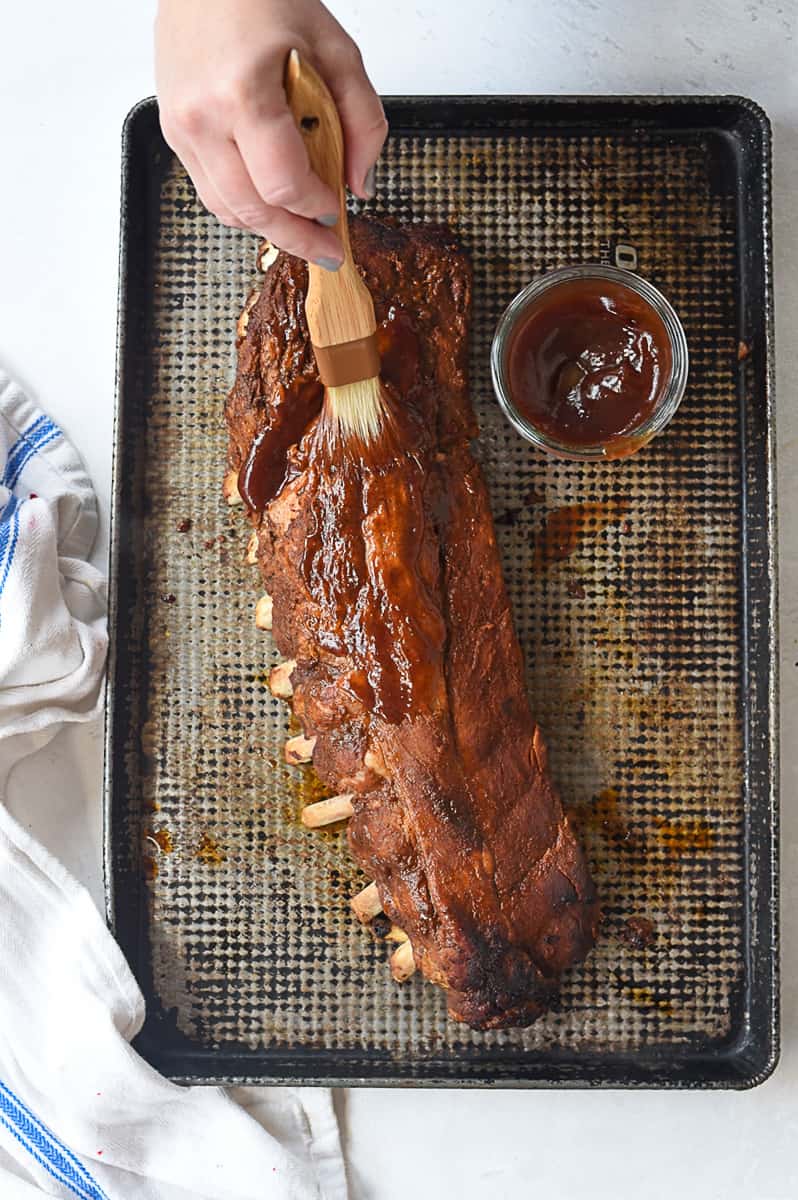 brushing BBQ sauce on ribs