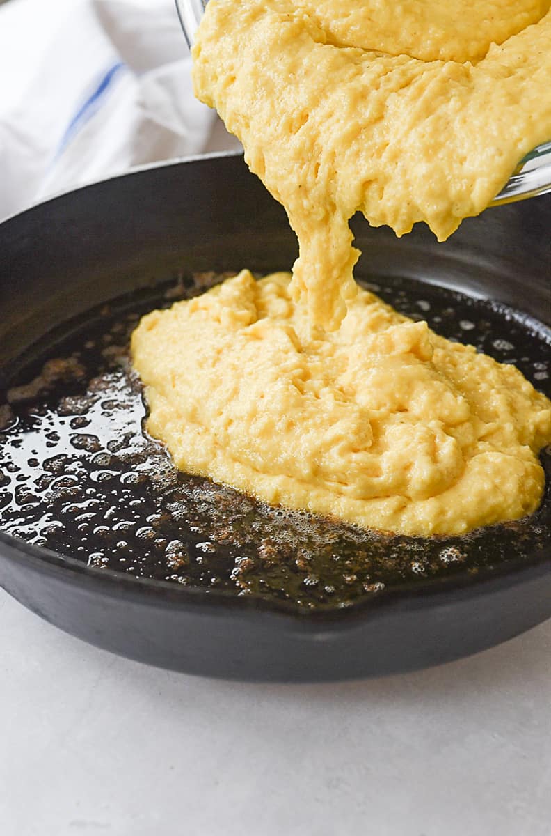 pouring cornbread batter into skillet