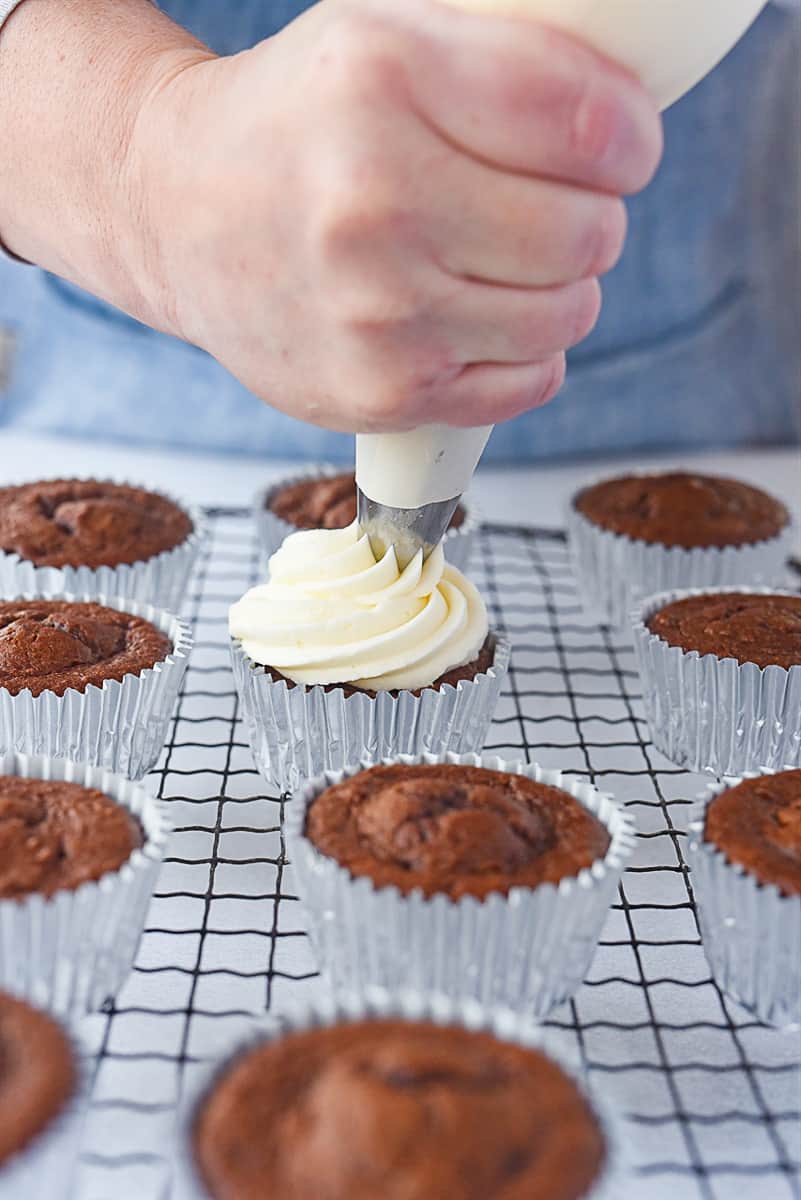 piping frosting onto cupcakes