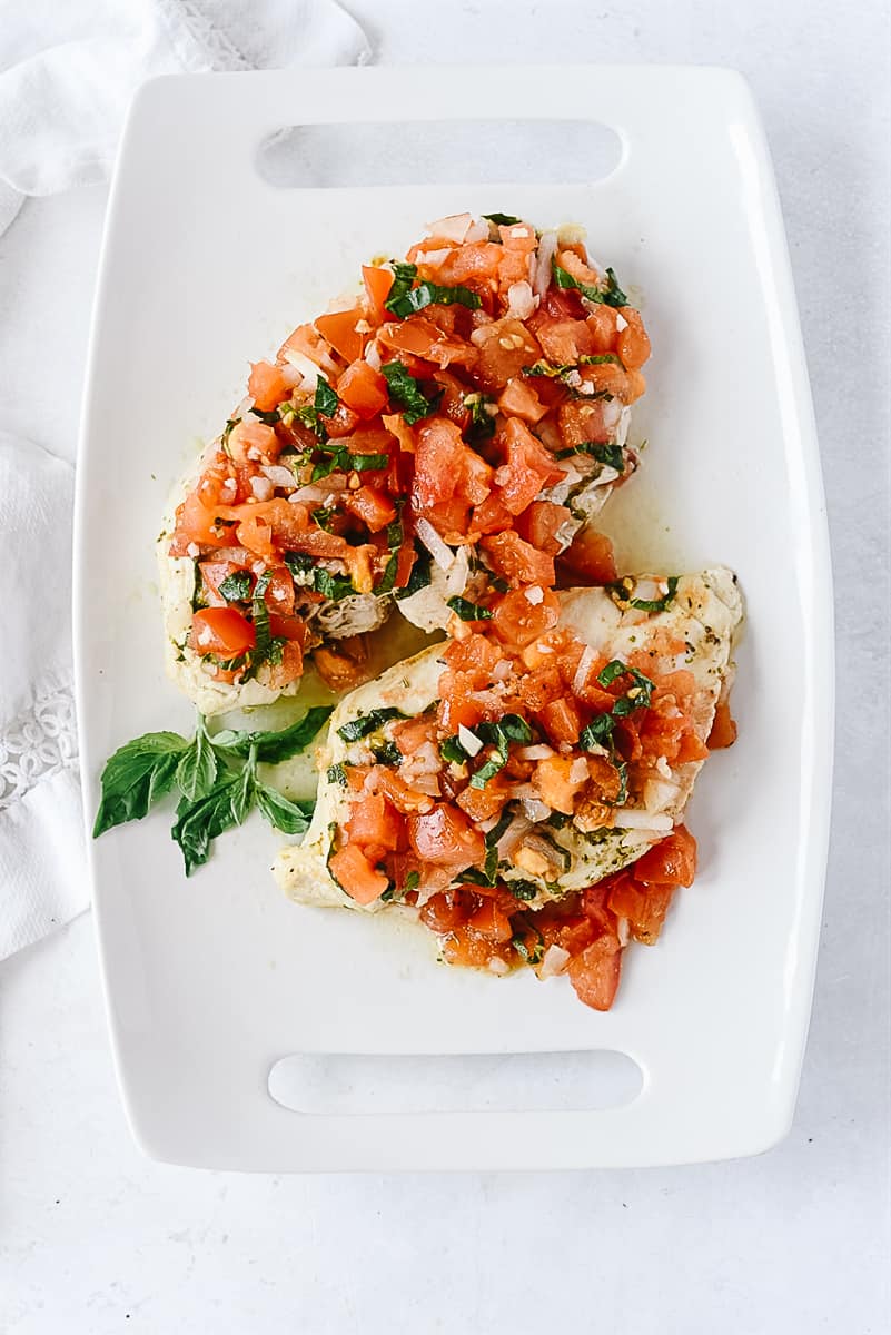 two chicken breasts with bruschetta on it
