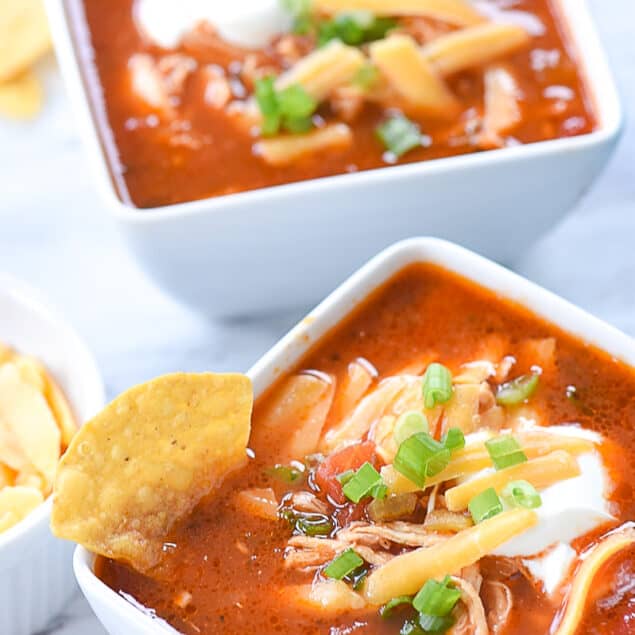 two bowls of enchilada soup with cheese on top