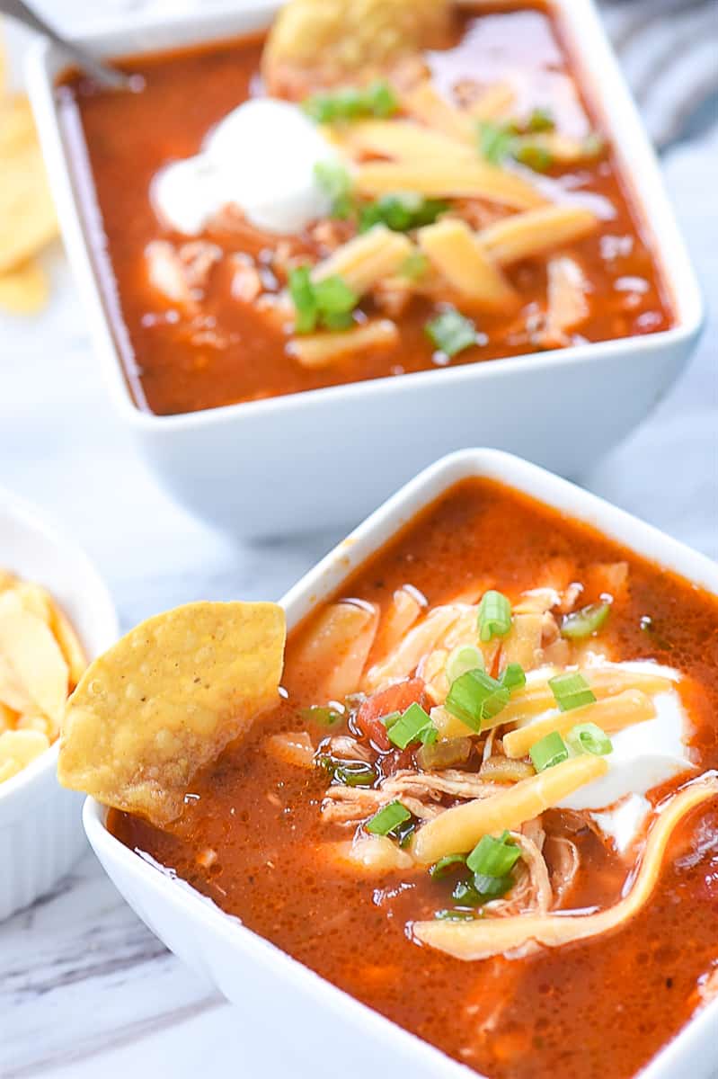 two bowls of enchilada soup with cheese on top