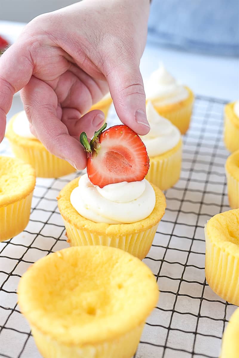 topping a cupcake with a strawberry