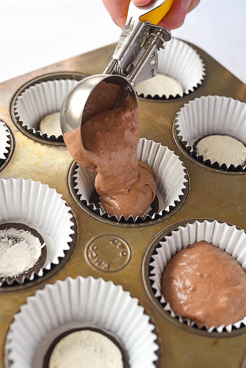 scooping cupcake batter into muffin tin