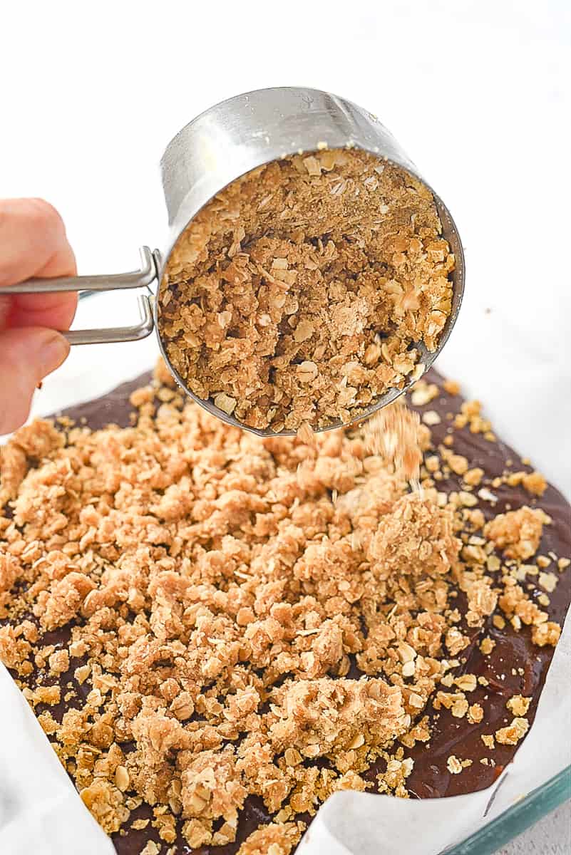 adding topping to chocolate oatmeal barsa