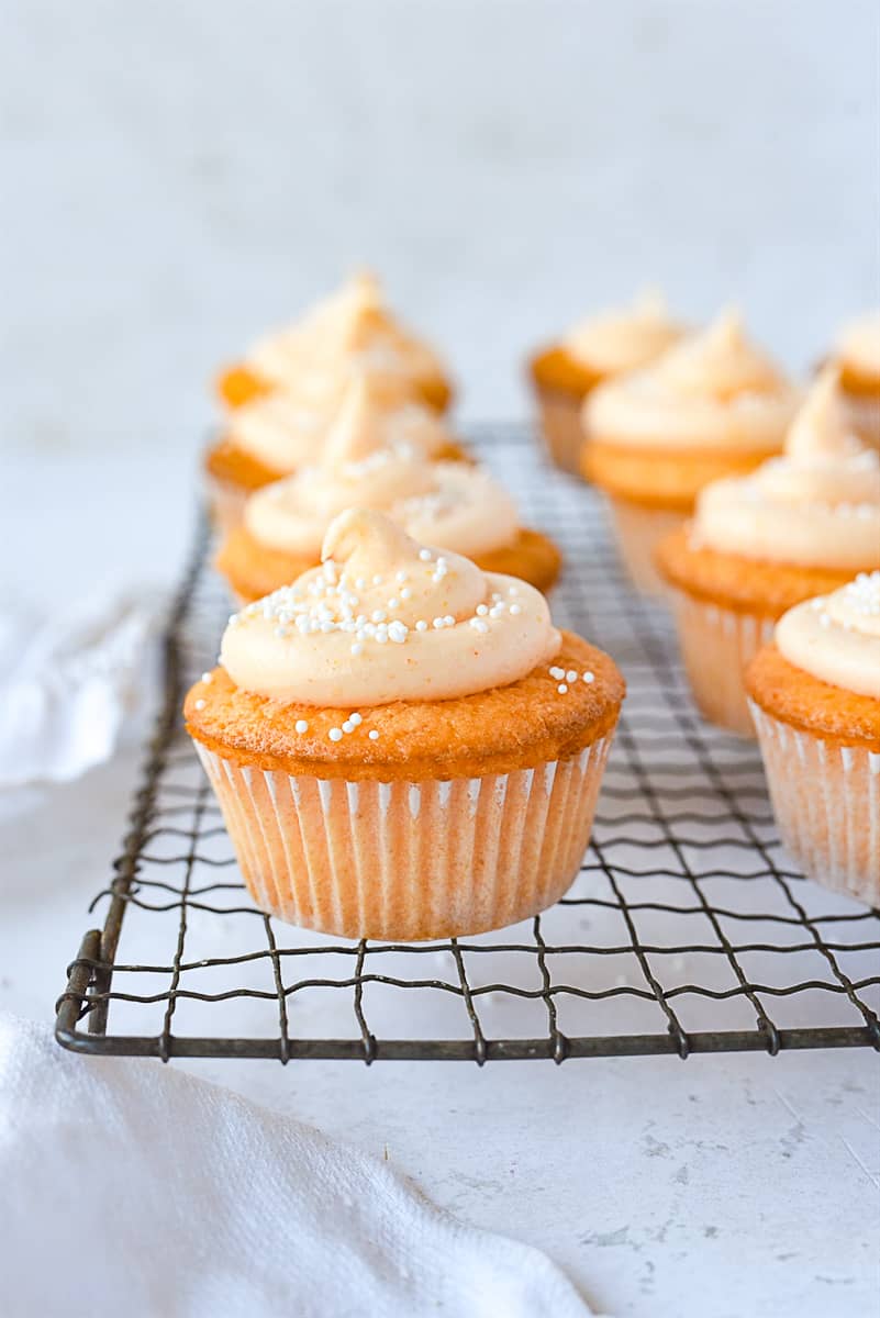 orange creamsicle cupcakes on a cooling rack