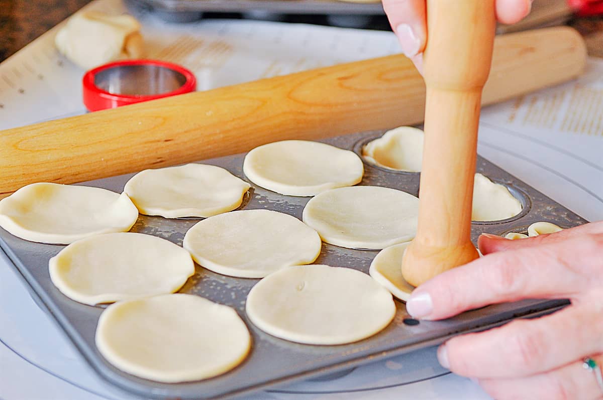 pushing dough down into muffin tin