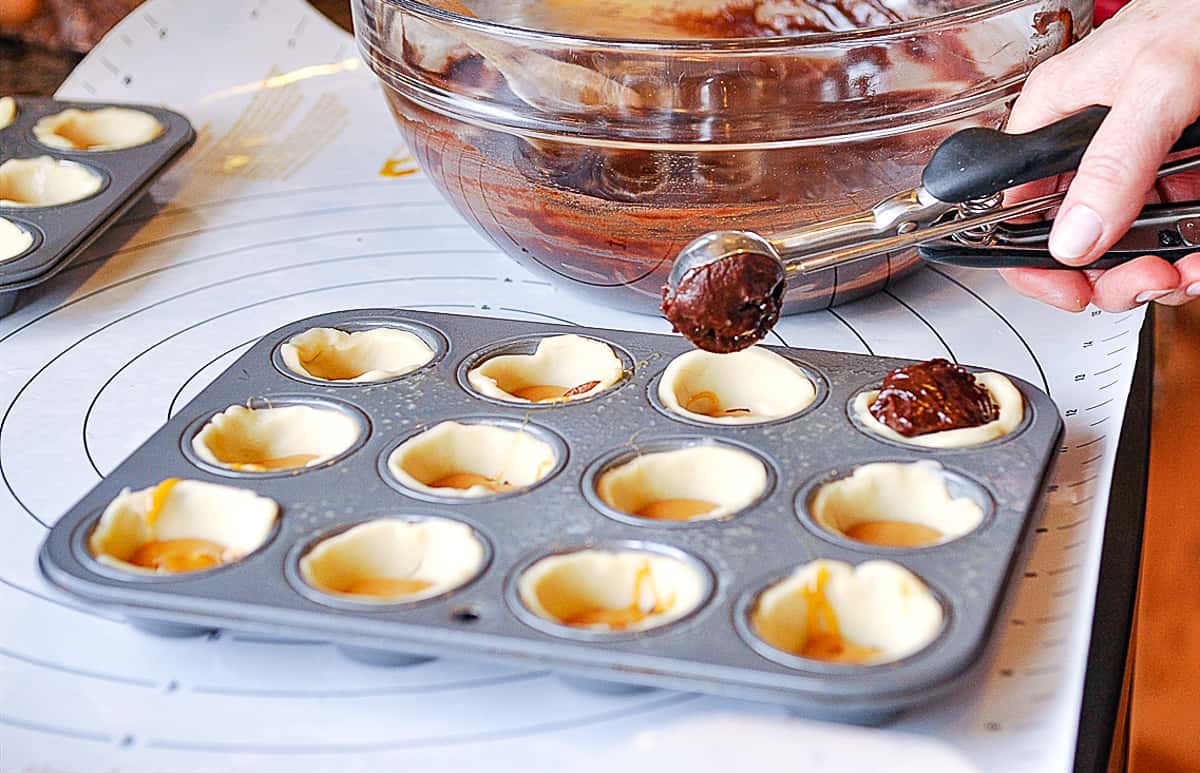adding brownie batter to muffin tin