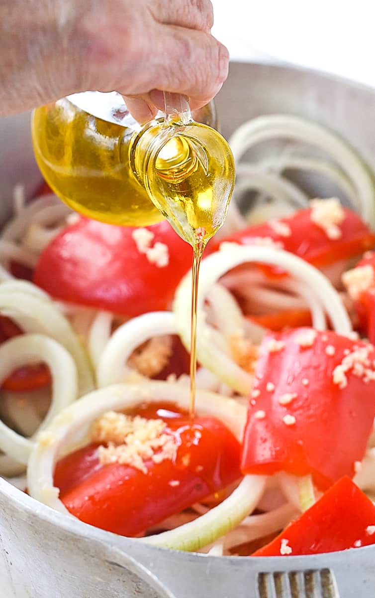 pouring oil over red peppers and onions