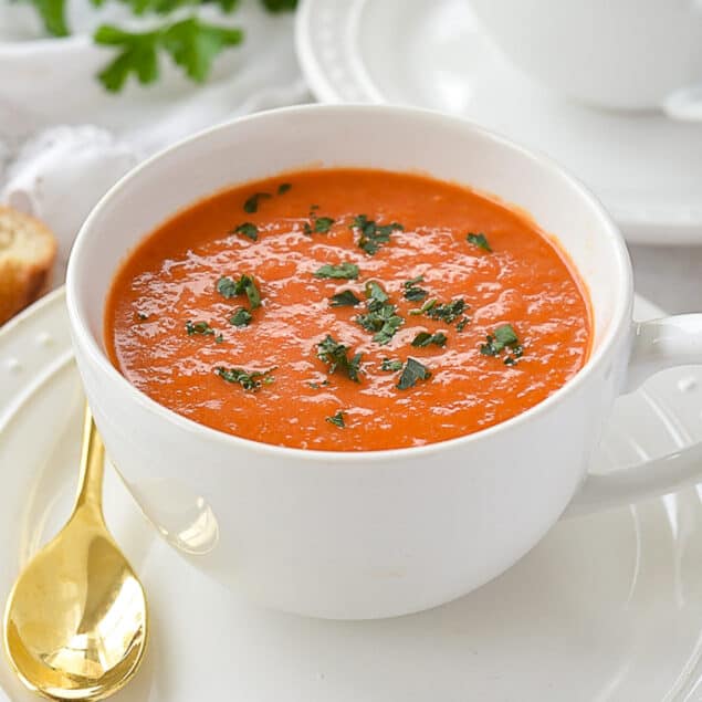 bowl of roasted red pepper soup with parsley on top