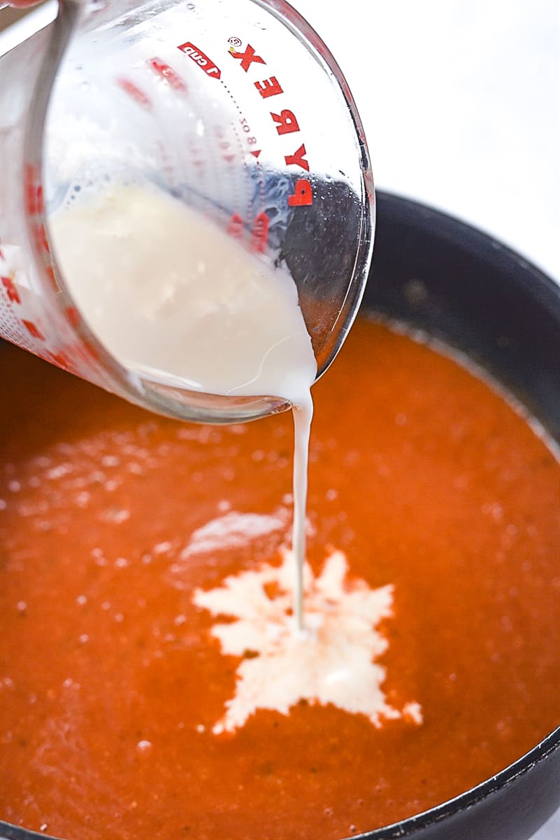 adding milk into butter chicken sauce