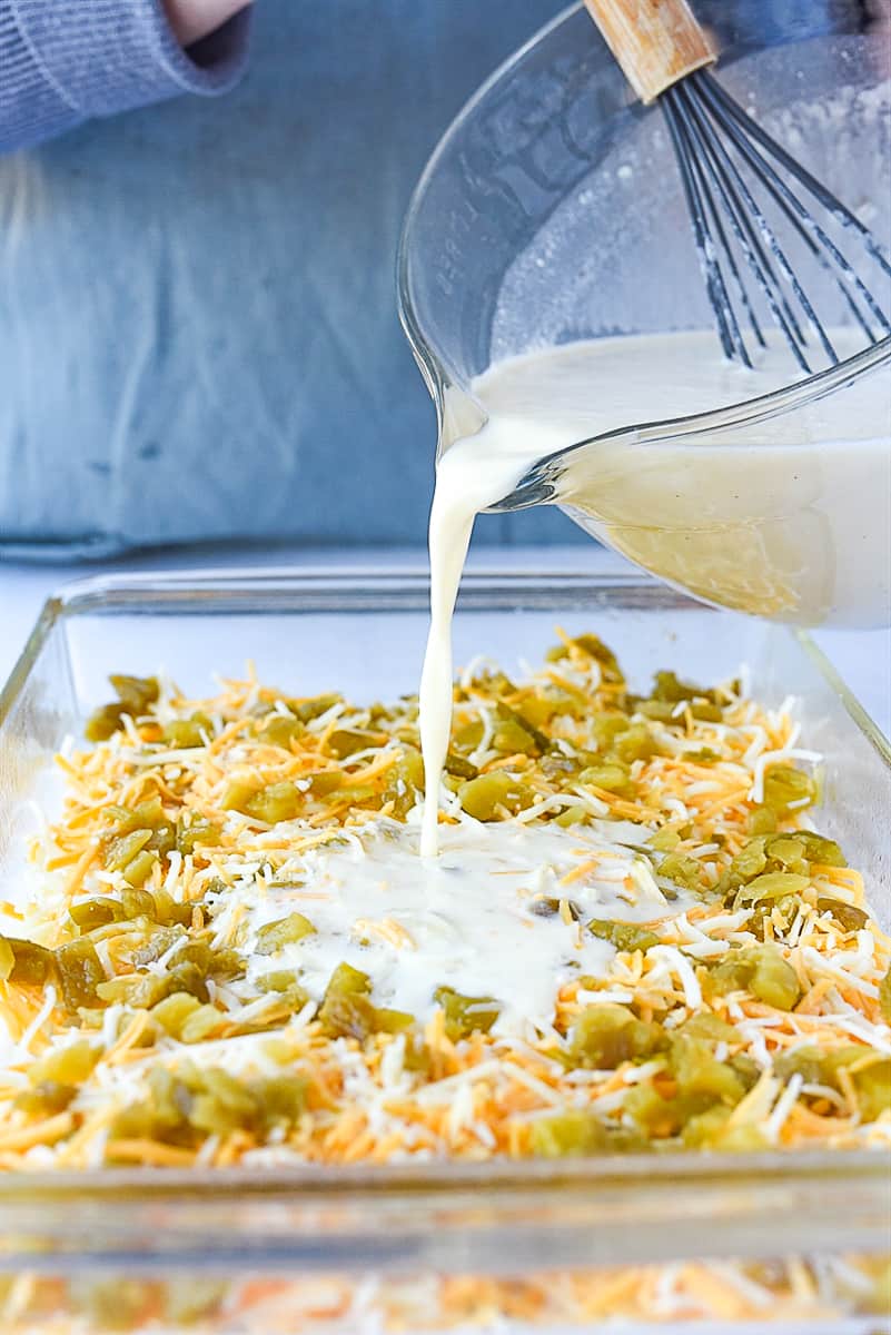 pouring milk over breakfast casserole