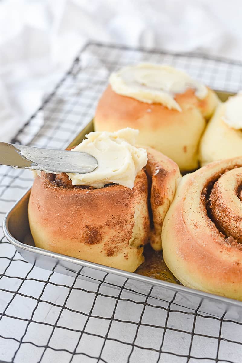 frosting a cinnamon roll