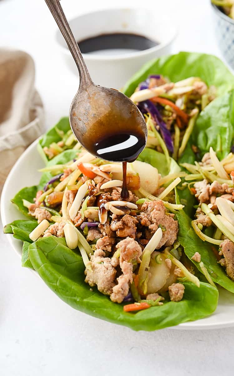 drizzling teriyaki sauce on lettuce wraps