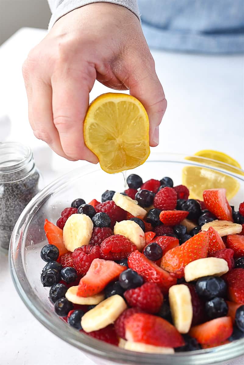 squeezing lemon on fruit salad