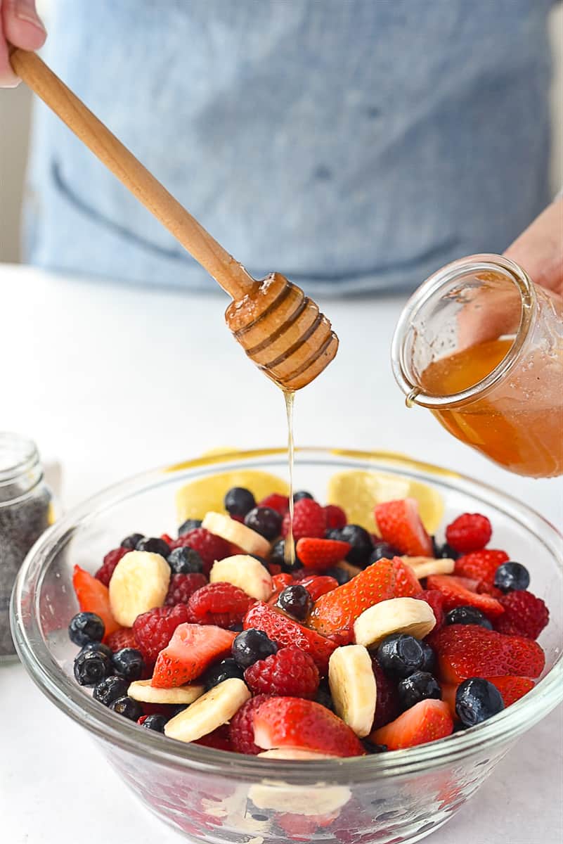 drizzling honey over fruit salad