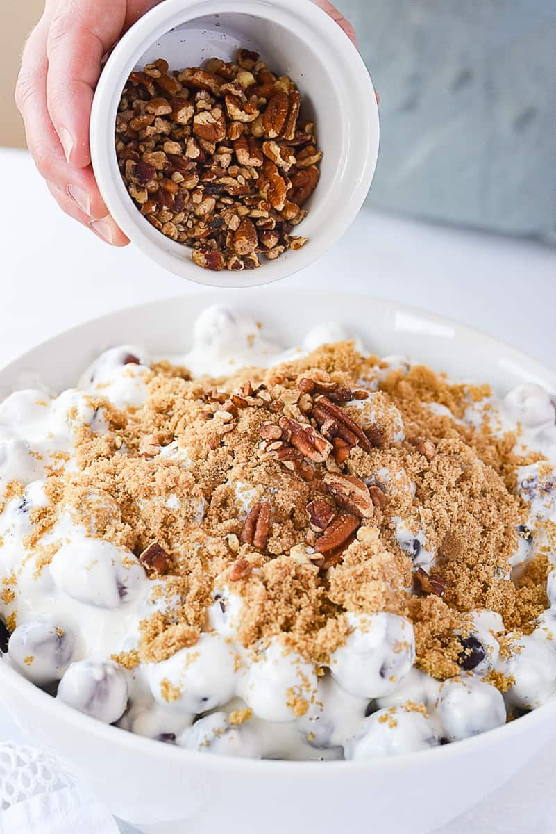 adding pecans to grape salad