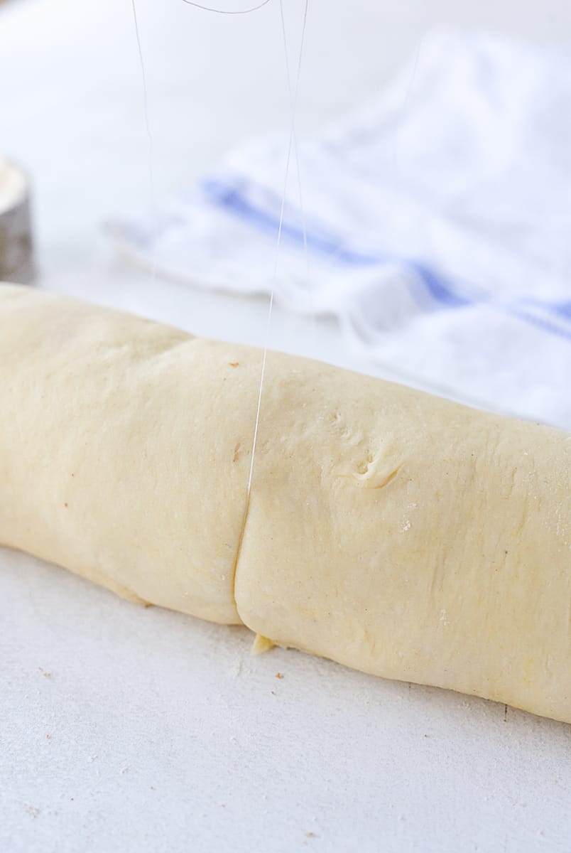 slicing cinnmon roll dough with thread