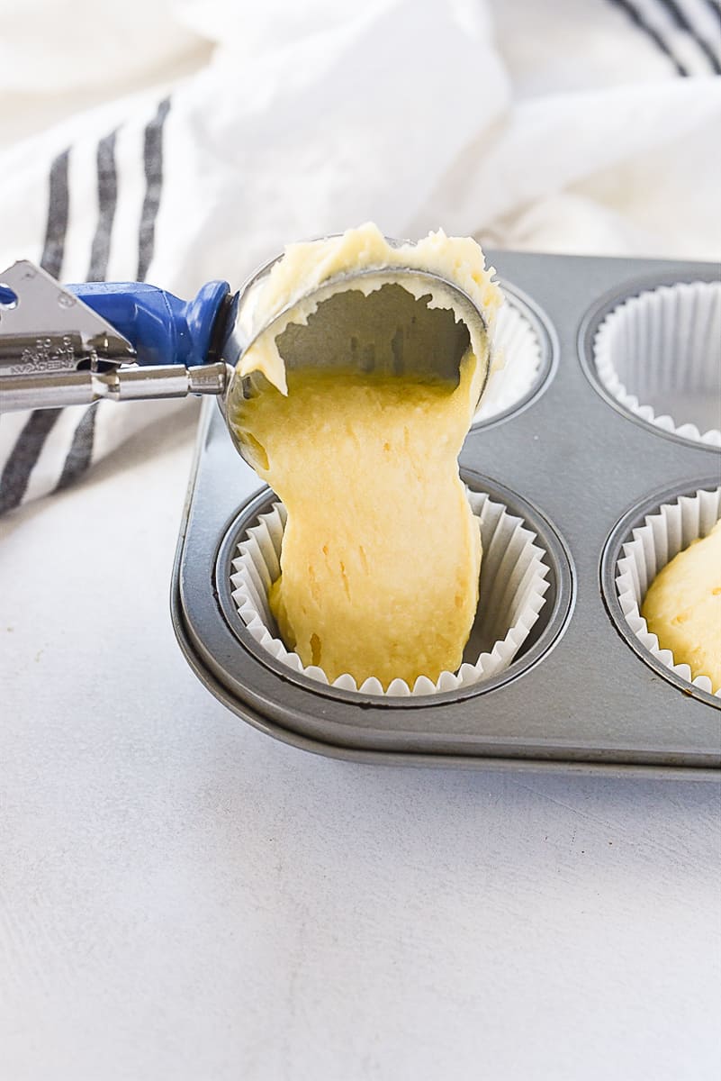 scooping cupcake batter into muffin tin