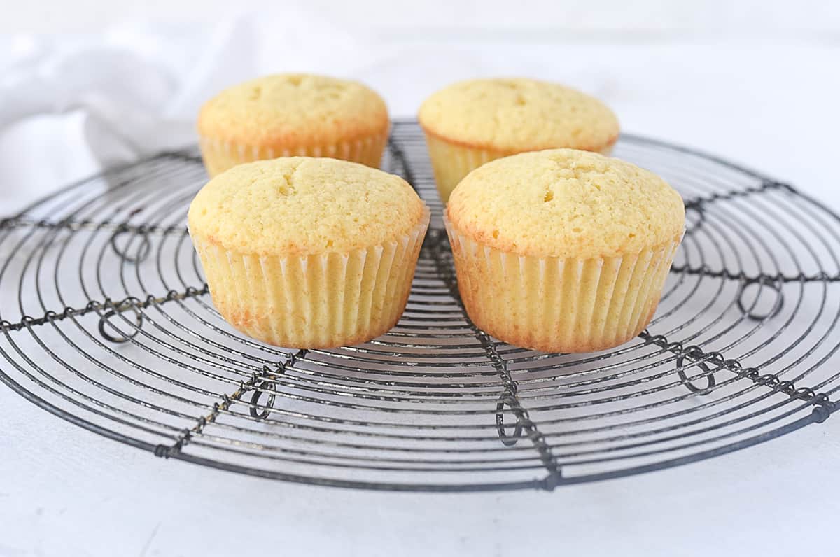 four unfrosted cupcakes on a rack