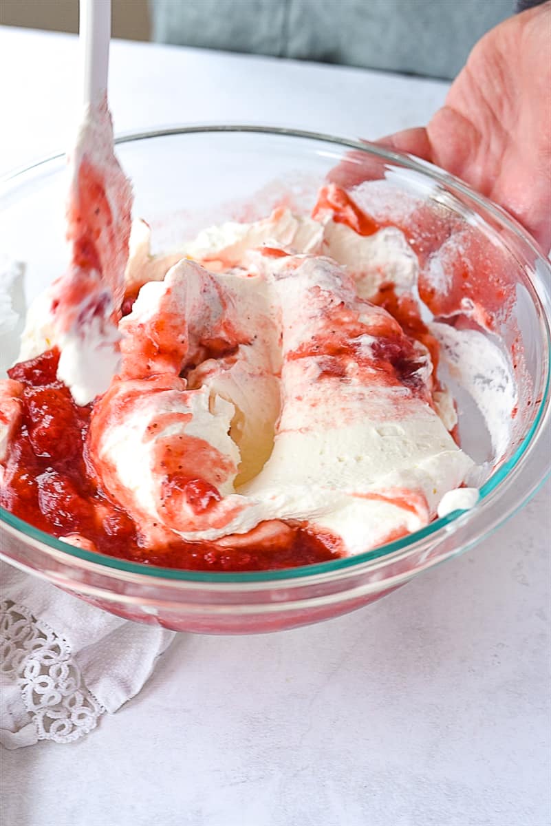 folding strawberries into whipped cream