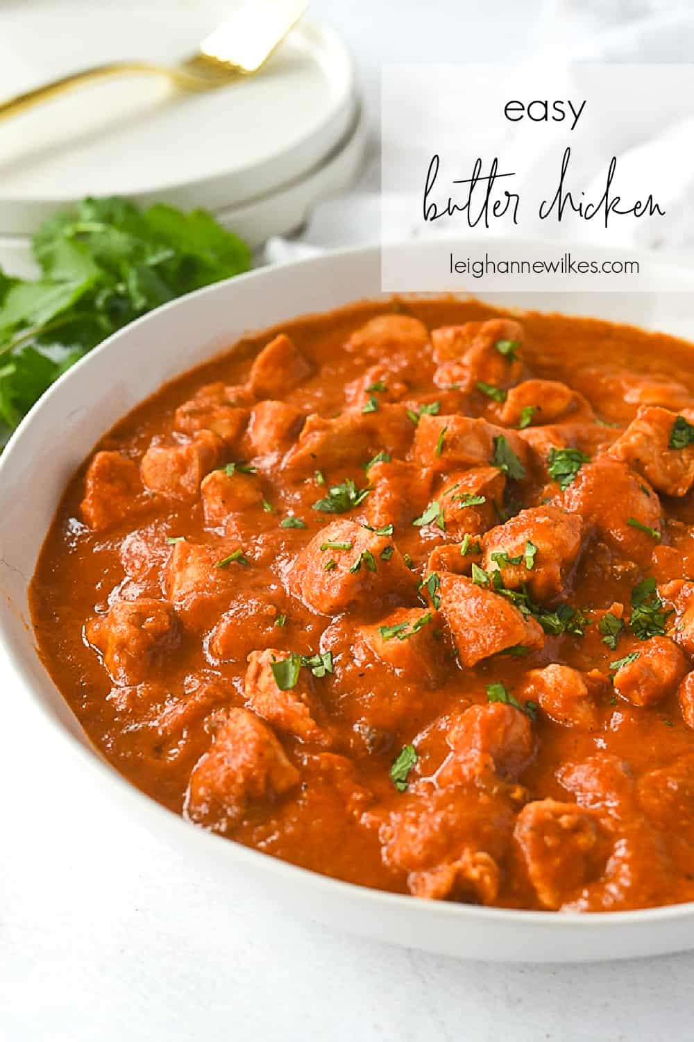 white bowl of butter chicken with cilantro on top