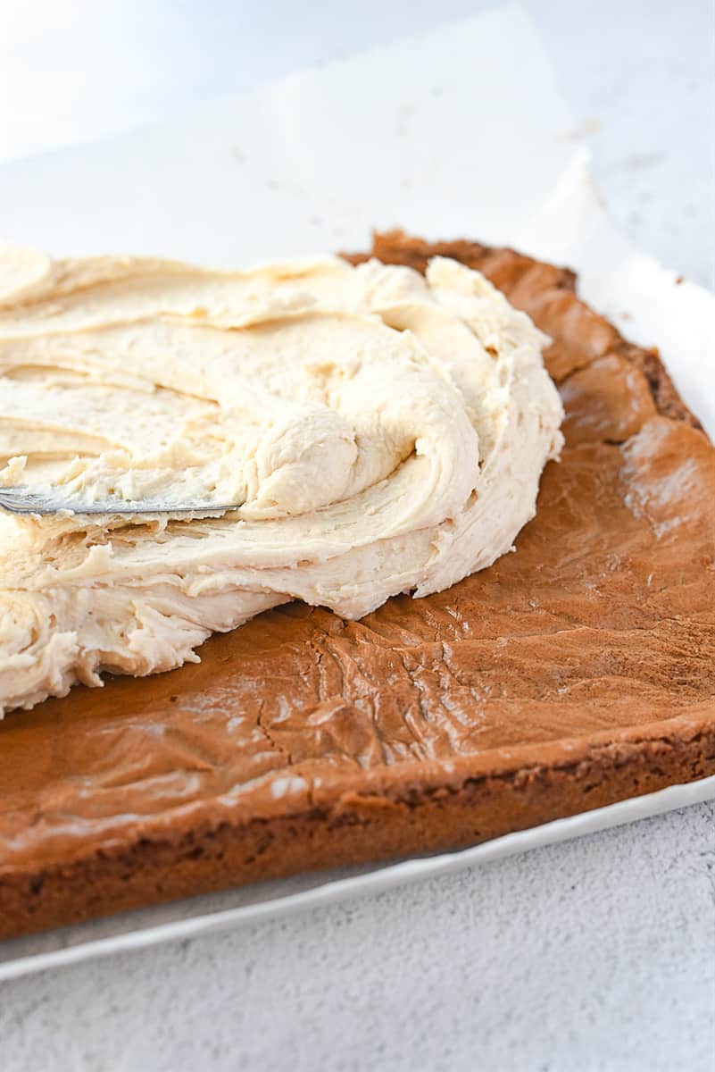 spreading brown butter frosting on brownies