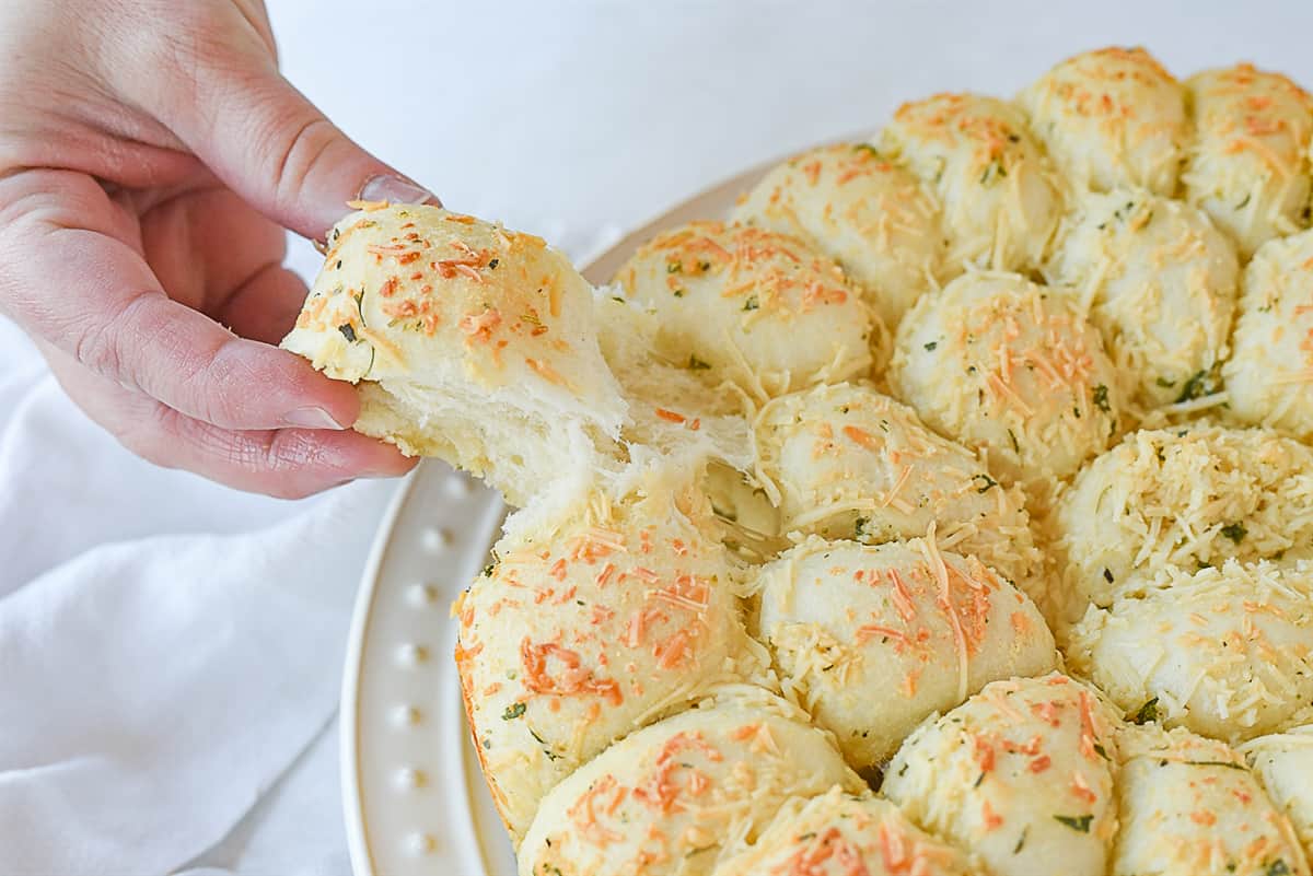 hand pulling a piece of cheesy garlic bread