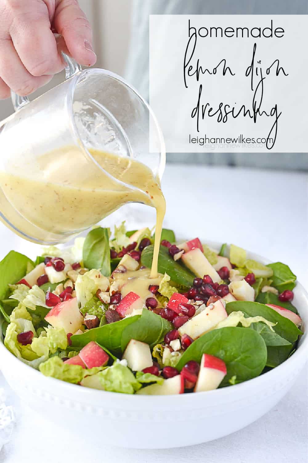 pouring lemon dijon salad dressing over salad