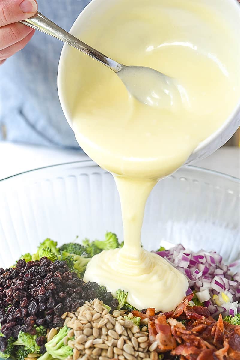 pouring dressing over broccoli salad
