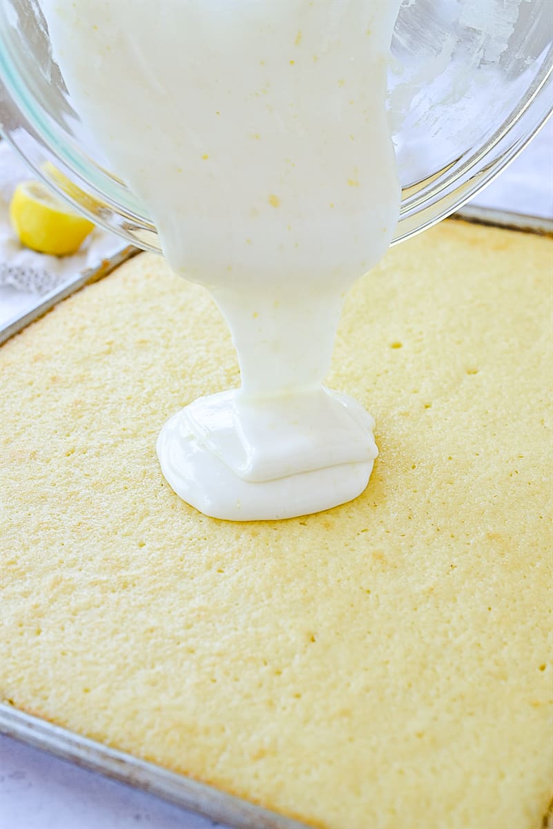 pouring frosting on lemon sheet cake