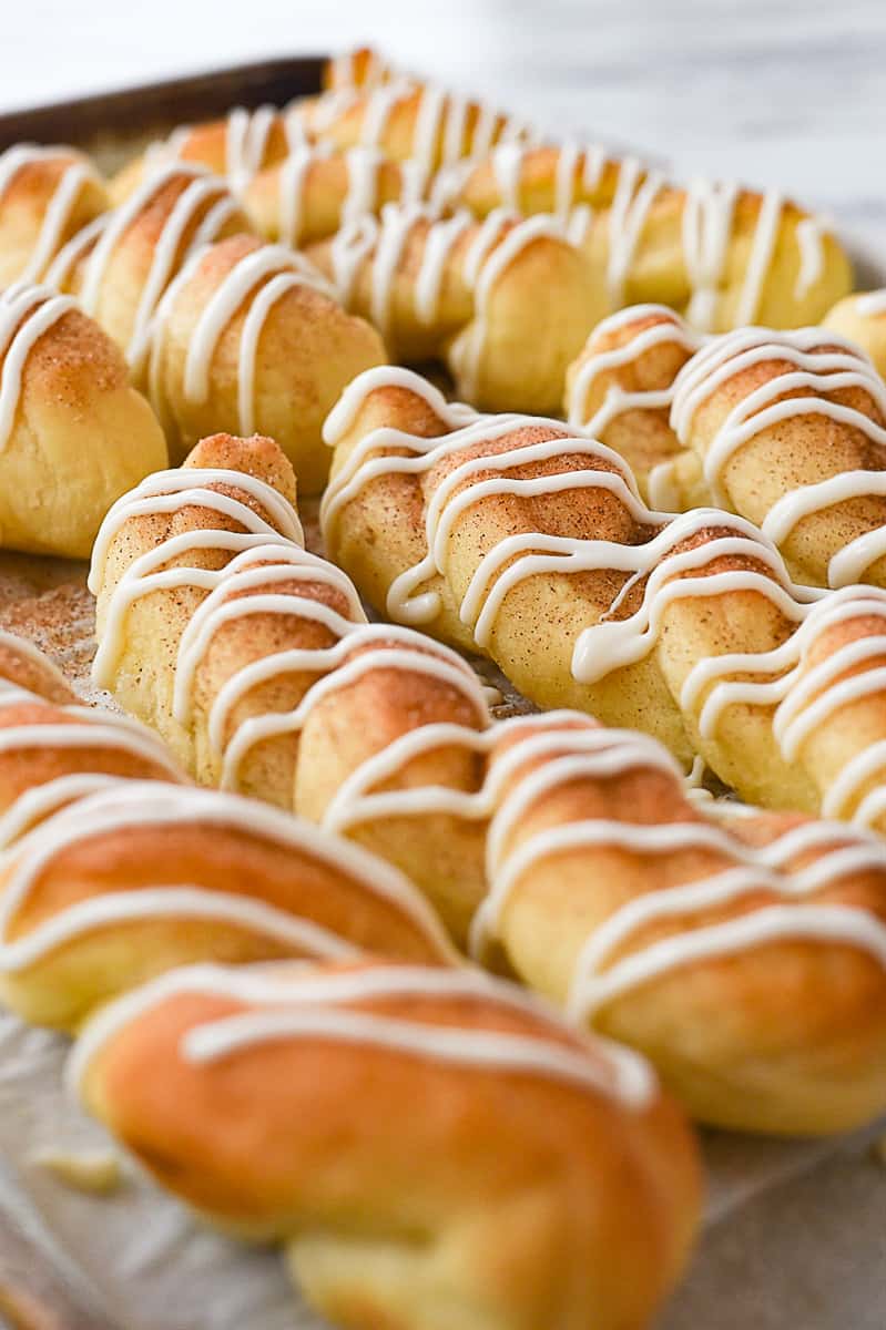 drizzled cinnamon breadsticks on baking sheet